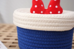 Detailed view of woven storage basket featuring red polka dot bow and cotton rope texture
