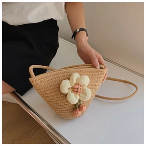 Detail of hand-woven mini bucket bag with white floral accent and pink pendant