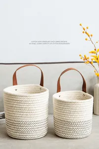 Detail view of woven cotton rope storage baskets with leather handles and gray zig-zag pattern
