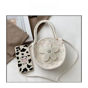 Détail d'un sac bandoulière rond en tricot avec grande fleur au crochet et perle centrale