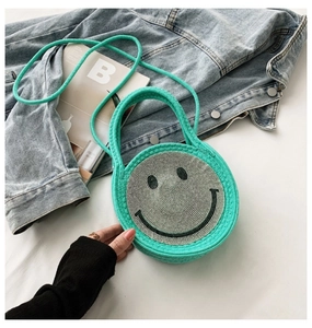 Détail d'un sac à bandoulière rond tressé vert menthe avec motif visage souriant en strass
