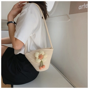 Detail of hand-woven cream mini bucket bag featuring a delicate floral accent for summer