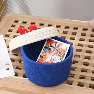 Cartoon cotton rope storage basket with red polka dot bow on wood table surface