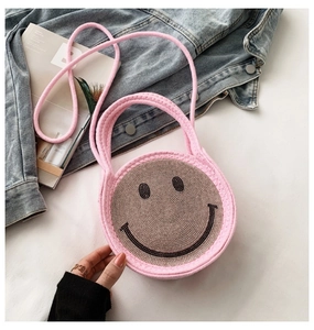 Détail d'un sac rond en tricot rose avec un smiley en strass et bandoulière tissée