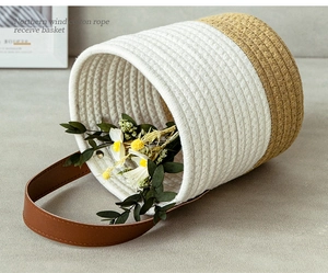 Detail of handwoven cotton rope storage basket with two-tone design and leather handle