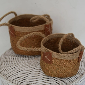 Detail view of woven sea grass baskets with rope handles and leather accents in two sizes