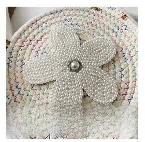 Détail du sac rond en tricot fait main avec fleur de perles et texture tissée