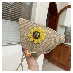 Detail of hand-woven crossbody bag with sunflower appliqué and pumpkin charms