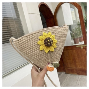 Detail of handmade straw crossbody bag with yellow sunflower and knit charm tassels