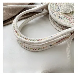 Gros plan d'un sac à main tissé crème avec motifs de vagues colorées et perles décoratives