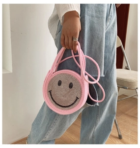 Détail d'un sac à main tissé rose avec un motif de smiley scintillant en strass