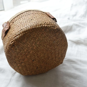 Detail of hand-woven seagrass basket with leather trim and cross-stitch on white cloth