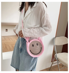 Gros plan sur le sac rond rose orné de strass avec un motif visage souriant en noir