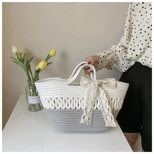 Detail of hand-woven rope tote bag with lace bow and stylish grey-white contrast knit design
