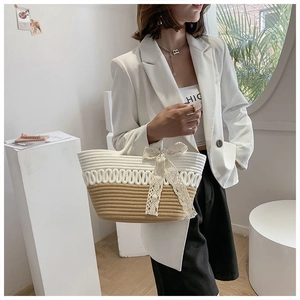 Detail of woven tote bag with lace bow and two-tone texture worn with white blazer