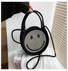 Détail d'un sac cabas tissé noir avec motif smiley en paillettes argentées et bandoulière
