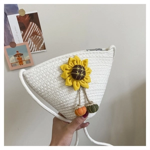 Detail of white straw bag with sunflower accent and decorative pom-poms on the side