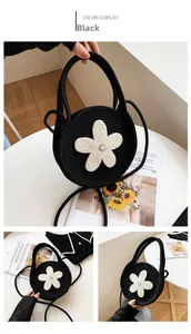 Détails d'un sac à main rond en tricot noir avec fleur en perles blanches et poignée