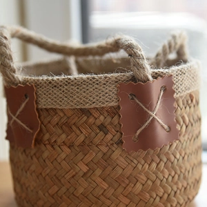 Handwoven seagrass basket with jute trim and rustic leather patch detail for storage