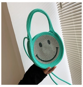 Détail du sac en paille tressée vert menthe avec smiley en strass et poignées rondes