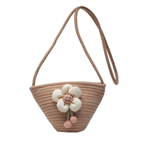Mini woven straw bucket bag with white floral accent and pink tassel for beach summer vacation