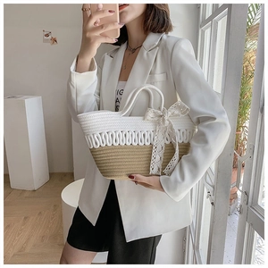 Detail of hand-woven straw tote bag with round hollow design and lace bow decoration