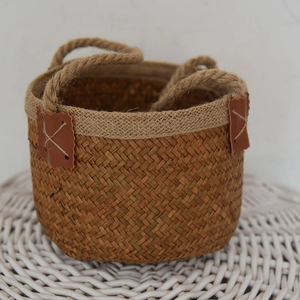 Detail of natural seagrass woven basket featuring brown leather patches and hemp handles