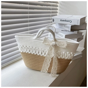 Close-up of woven straw handbag featuring contrast colors and a delicate lace bow detail