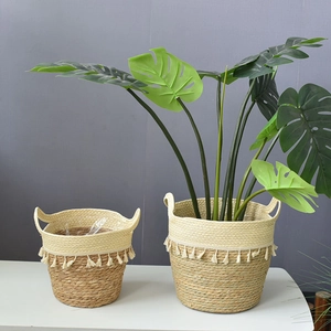 Macro detail of hand-woven seagrass planter basket with white fringe tassels and handles