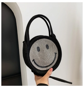Détail d'un sac à main rond tissé noir orné d'un motif smiley étincelant en strass argentés
