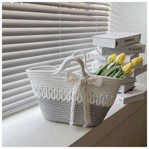 Detail view of woven rope tote with gray contrast base and white bow decoration