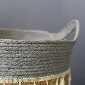 Detail of hand-woven straw basket with grey fiber stitching and cotton tassel fringe