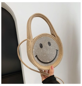 Détail du sac à main en paille tissée avec un motif smiley brillant en strass chic