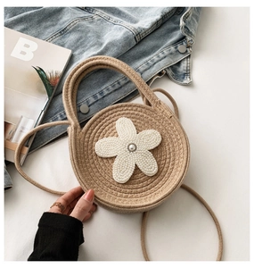 Détail du sac tissé rond avec fleur de perles et poignée supérieure circulaire