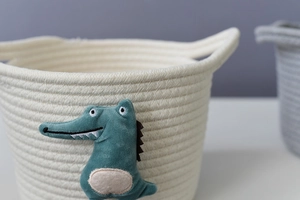 Detail of hand-woven cotton rope storage basket featuring a green crocodile animal patch