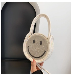 Détail d'un sac rond en paille avec smiley en strass et coutures ondulées colorées