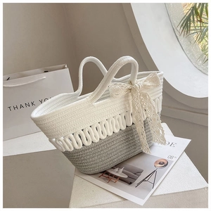 Detail of hand-woven rope tote bag with bicolor wave pattern and white lace bow