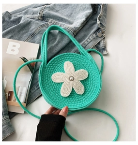 Détail du sac rond en tricot vert menthe avec grande décoration de fleur en perles