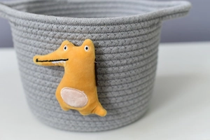 Detail of grey cotton rope storage basket with yellow plush crocodile and sturdy handles