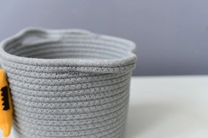 Close-up of cotton rope weaving texture and sturdy handle on a gray storage basket