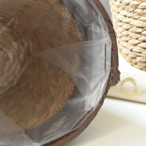 Close-up of woven seagrass basket showing waterproof plastic liner and brown stitching detail