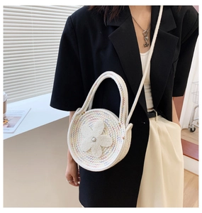 Détail du sac tricoté rond tissé à la main avec fleur en perles blanches et bandoulière