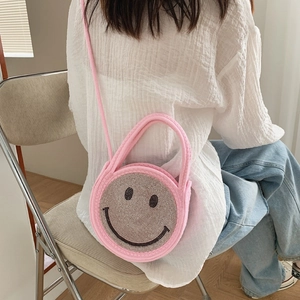 Sac à main rond rose en maille avec smiley en strass porté par un mannequin