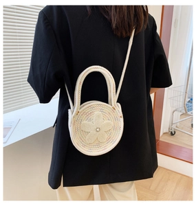 Détail du sac à bandoulière rond en maille crème avec fleur en perles et poignée supérieure