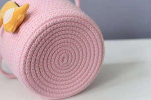 Detailed close-up of pink cotton rope weave storage basket with yellow fox plush decoration