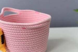 Detailed close-up of pink cotton rope woven basket featuring a yellow sunflower decor
