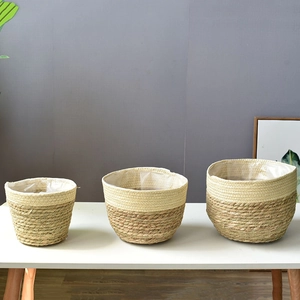 Detailed view of three handmade seagrass planters with waterproof plastic liners on a white table
