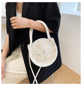 Détail du sac rond en tricot blanc avec fleur en perles et coutures ondulées colorées