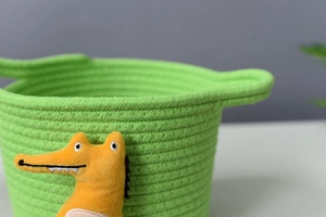 Detailed macro view of green cotton rope basket with cute orange crocodile plush toy ornament