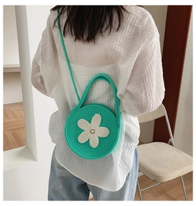 Détail d'un sac bandoulière en tricot vert menthe avec fleur blanche et perle décorative